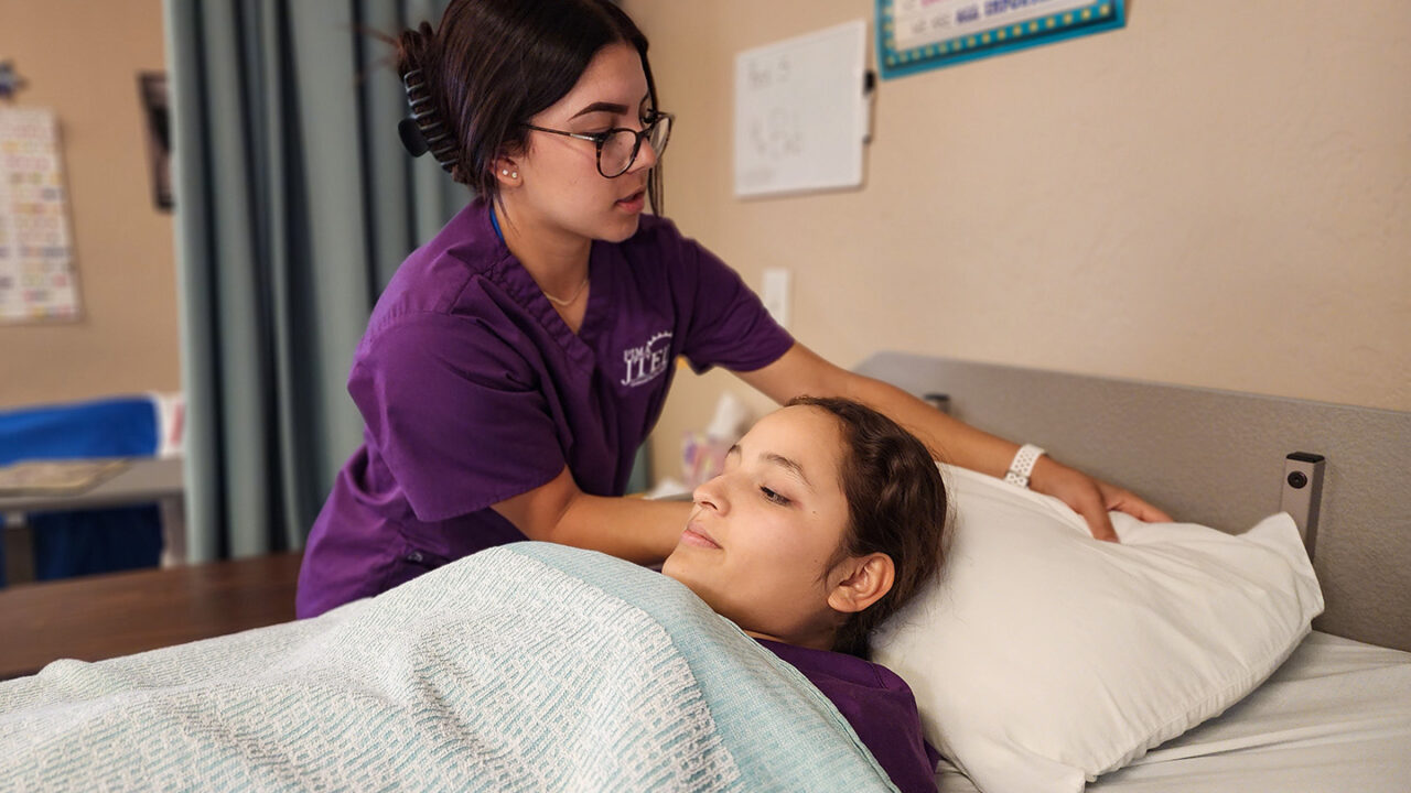 Nursing student replacing pillow case on occupied bed