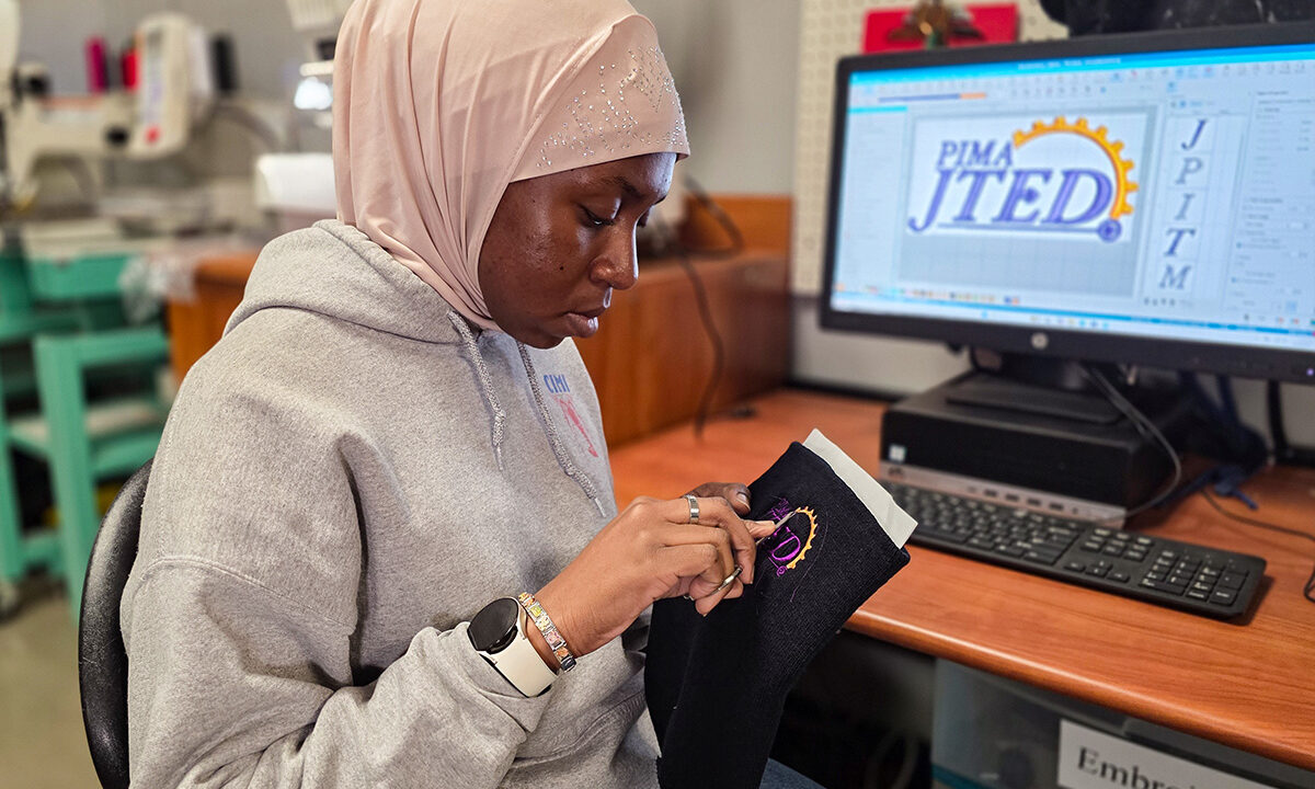 Student removing threads from stitched beanie