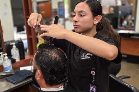 Cosmetology student cutting man's hair