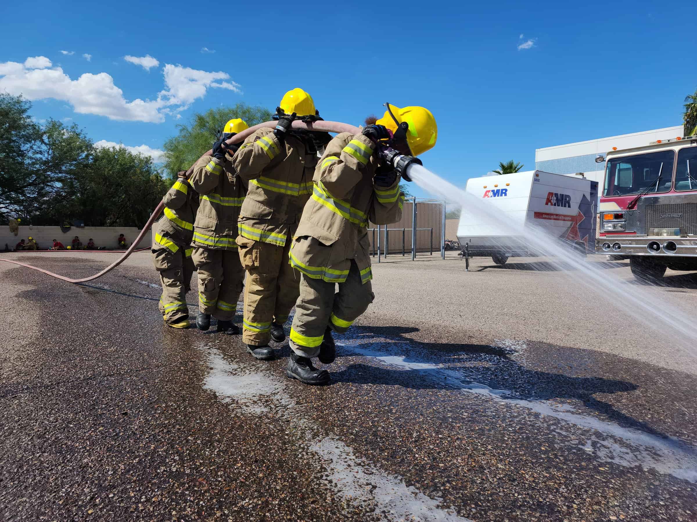 Four students carrying and spraying hose