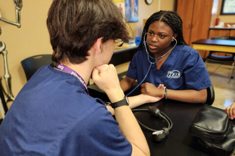Student taking blood pressure of another student
