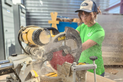 Student cutting wood with saw