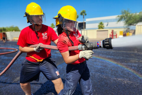 Students aiming fire hose