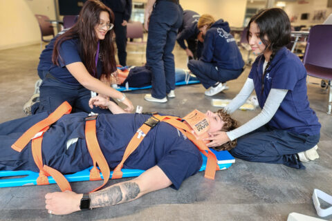 Students strapping patient to backboard