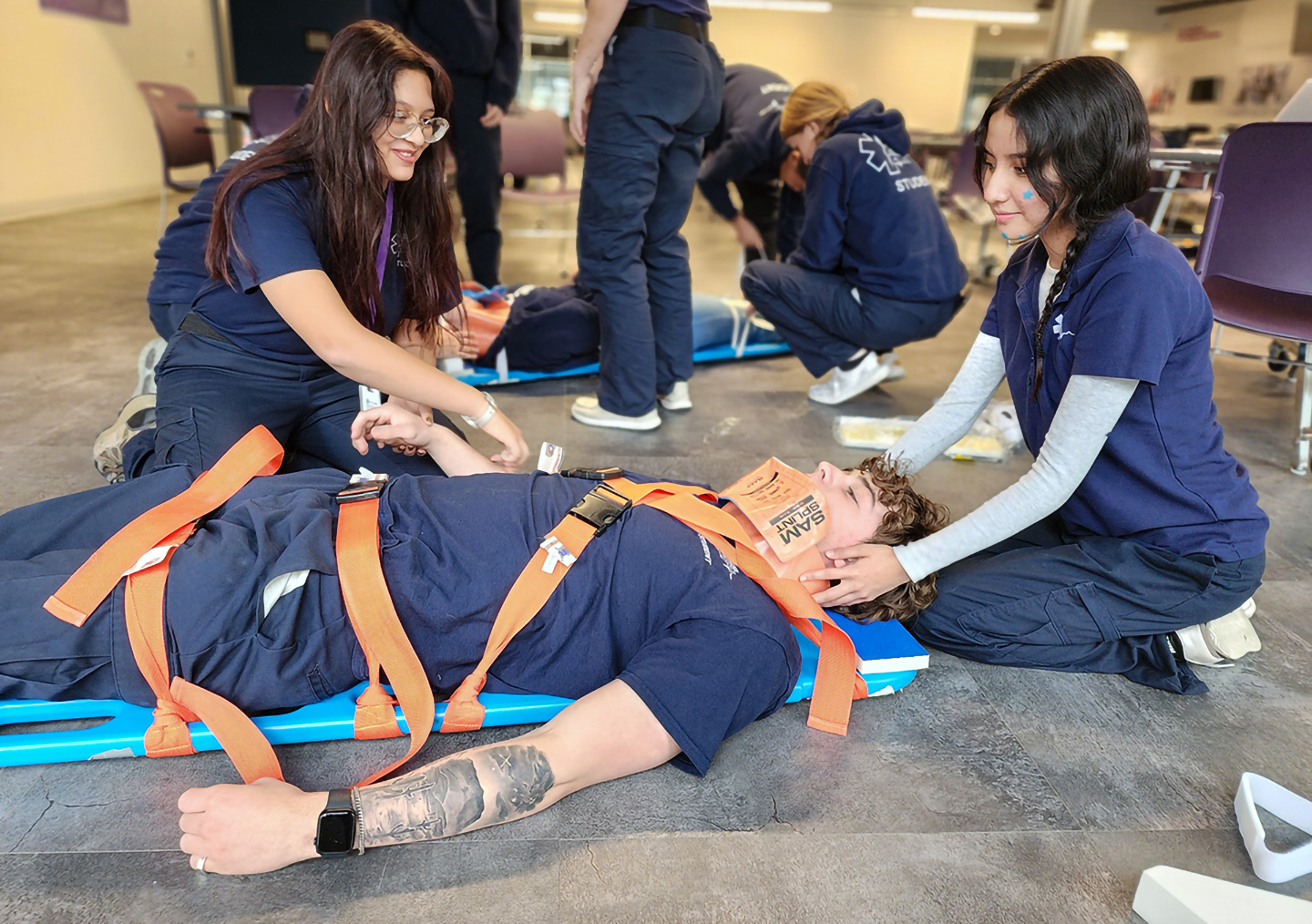 Students strapping patient to backboard