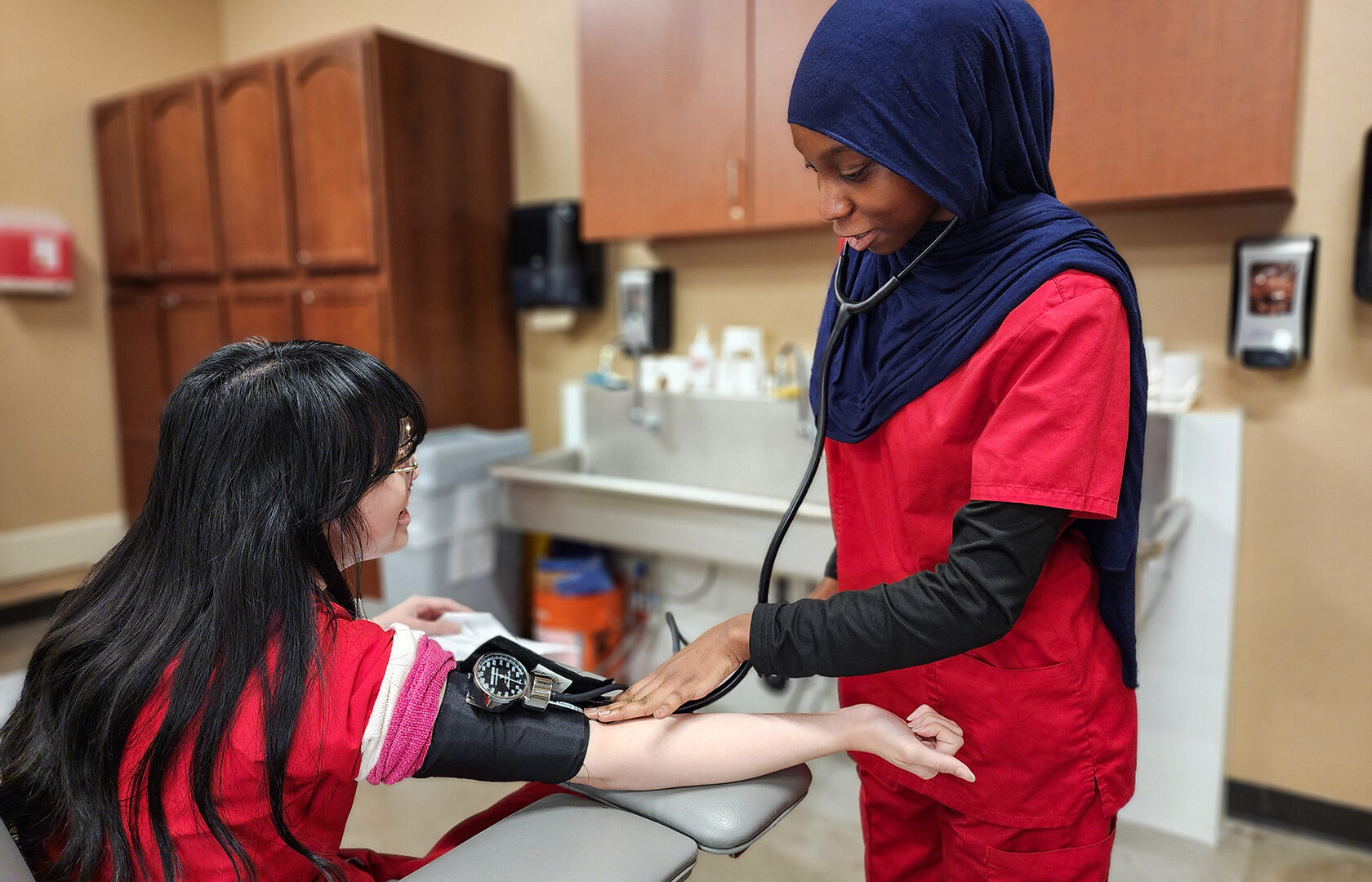 Student finding pulse using blood pressure cuff