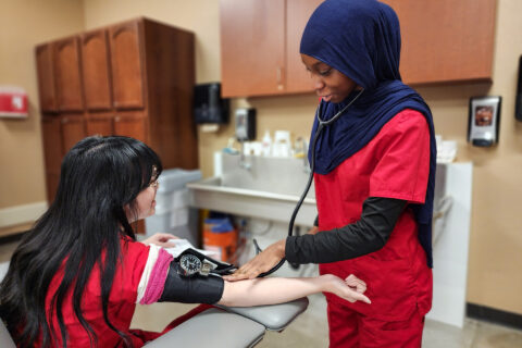 Student finding pulse using blood pressure cuff