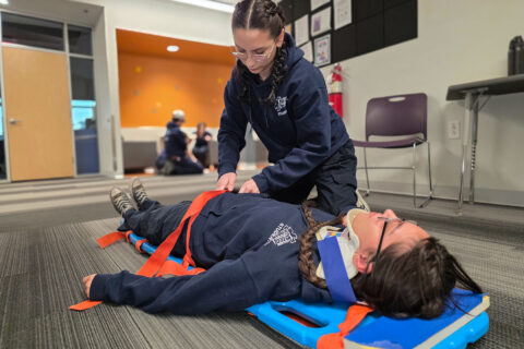 Student strapping patient to body board
