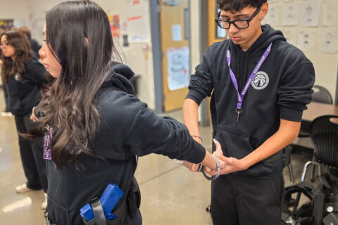 Student applying handcuffs to other student