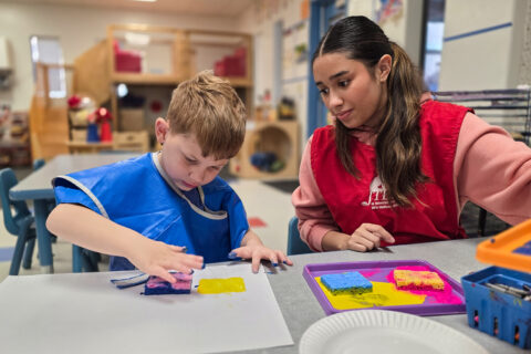 High school student helping preschooler paint