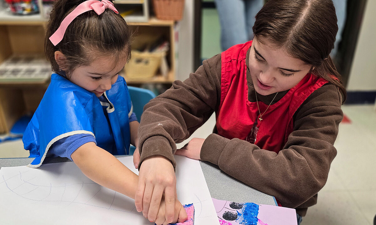 High school student helping preschooler paint