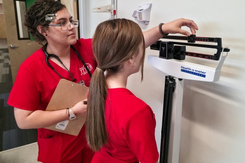 Student measuring patient's weight