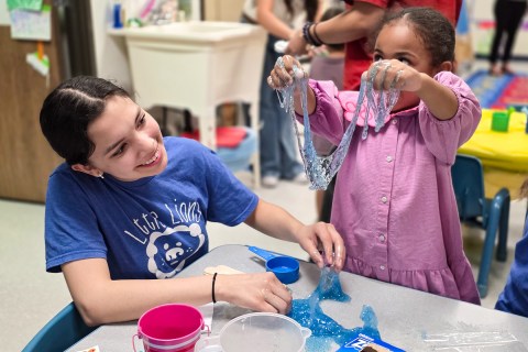 Student helping preschooler make slime