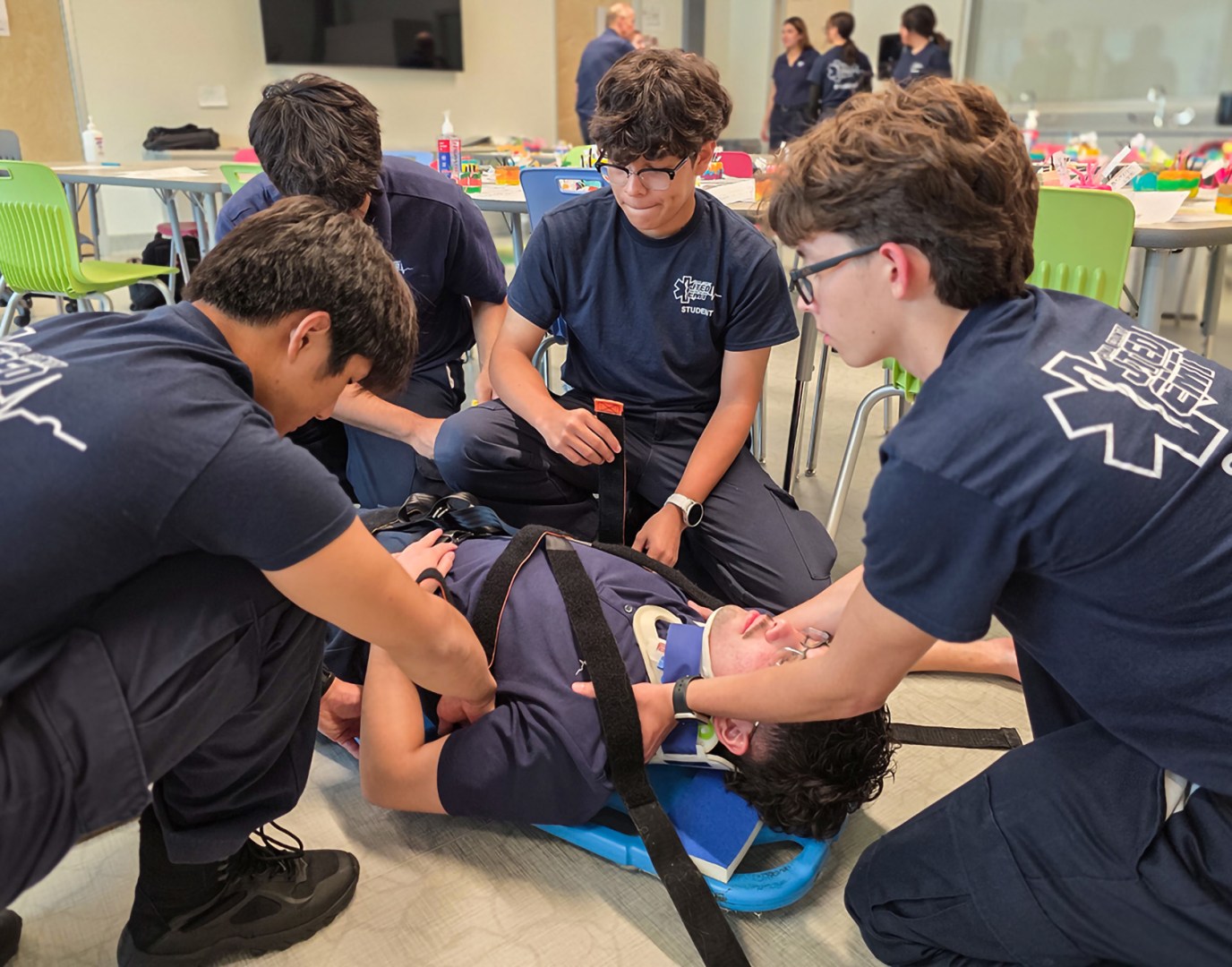 EMT Students strapping patient to back board
