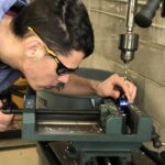 male precision machining student using a drill press