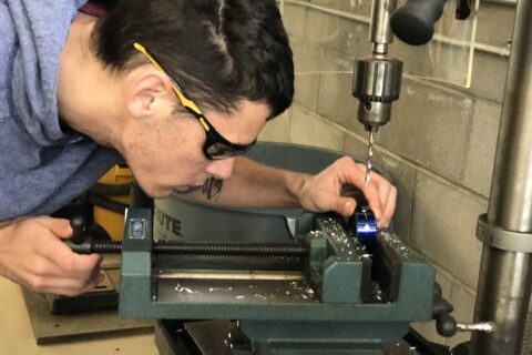 male precision machining student using a drill press
