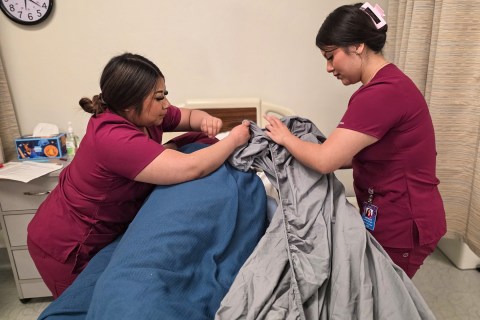Caregiver students making occupied bed
