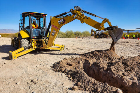 Student digging trench with backhoe