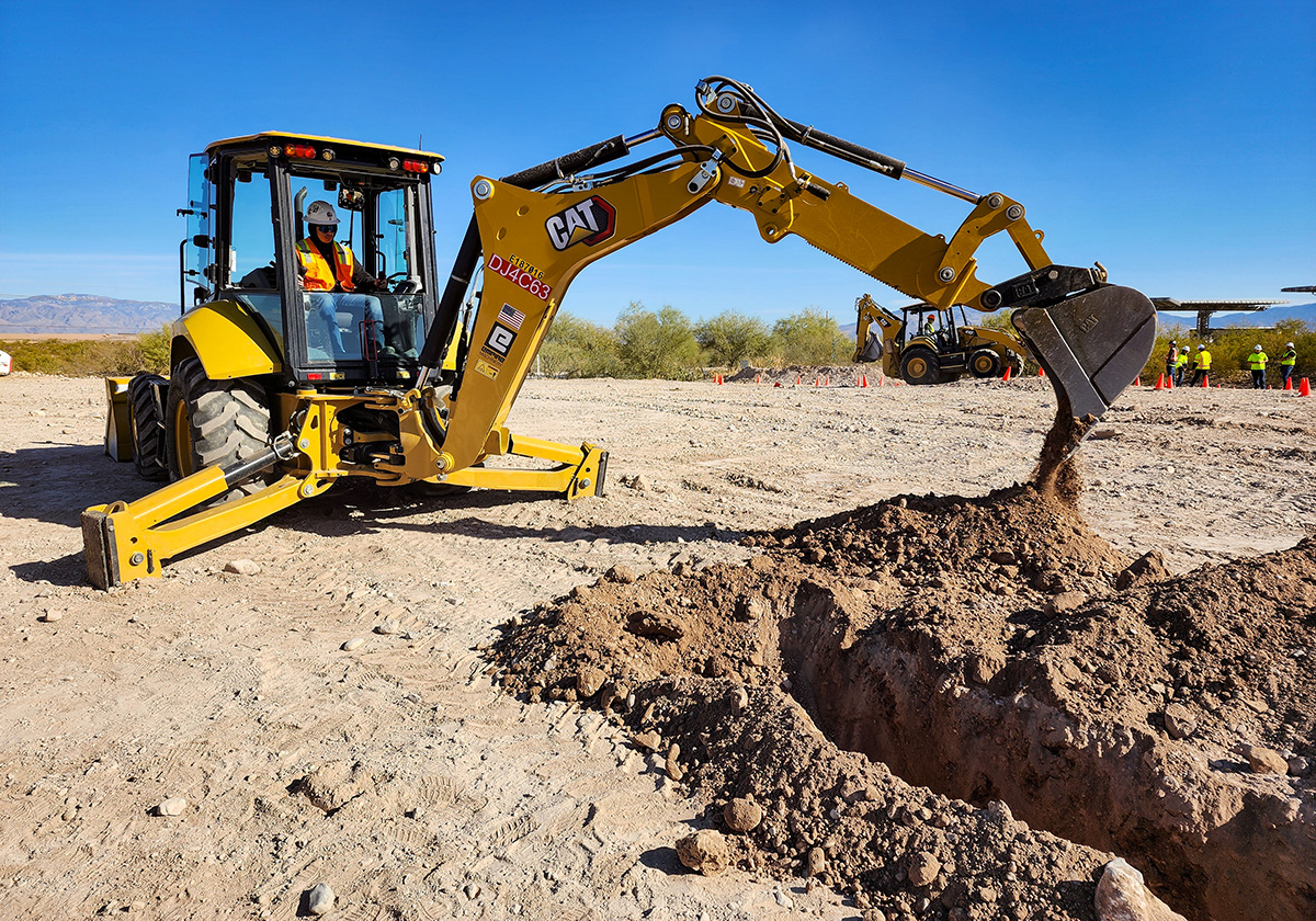 Student digging trench with backhoe