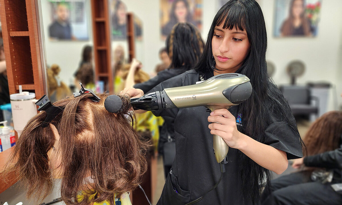 Cosmetology student blowdrying mannequin hair
