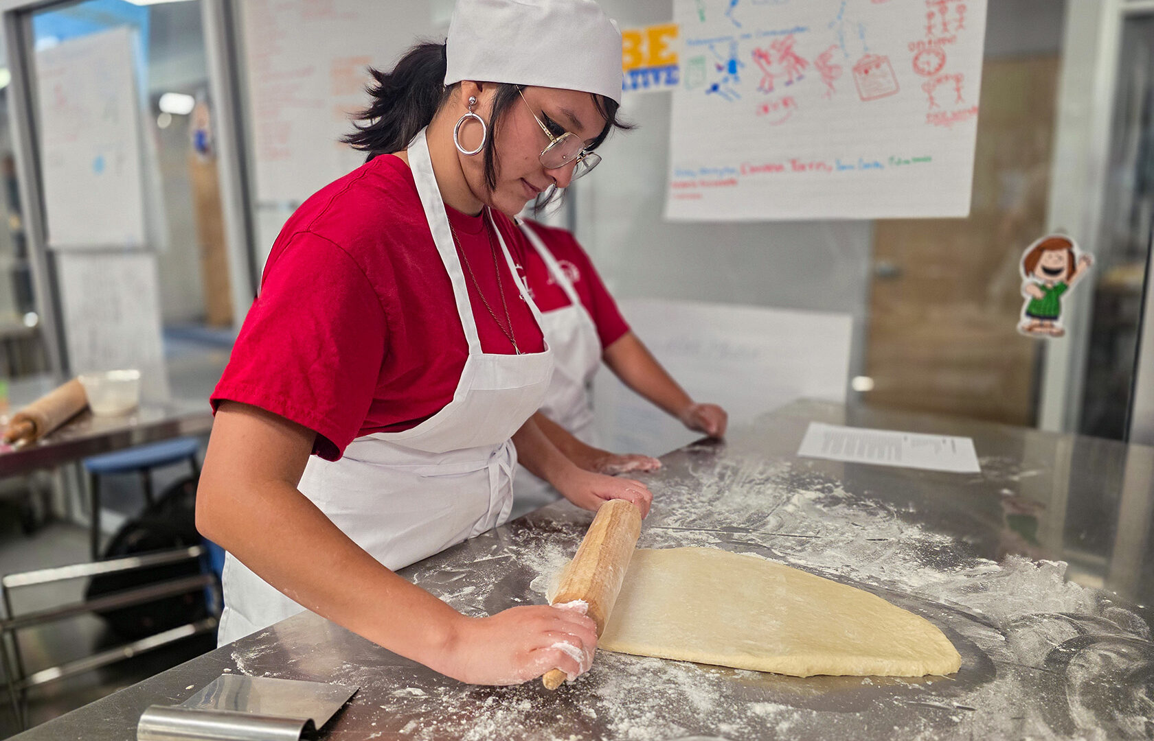 Student rolling dough with rolling pin