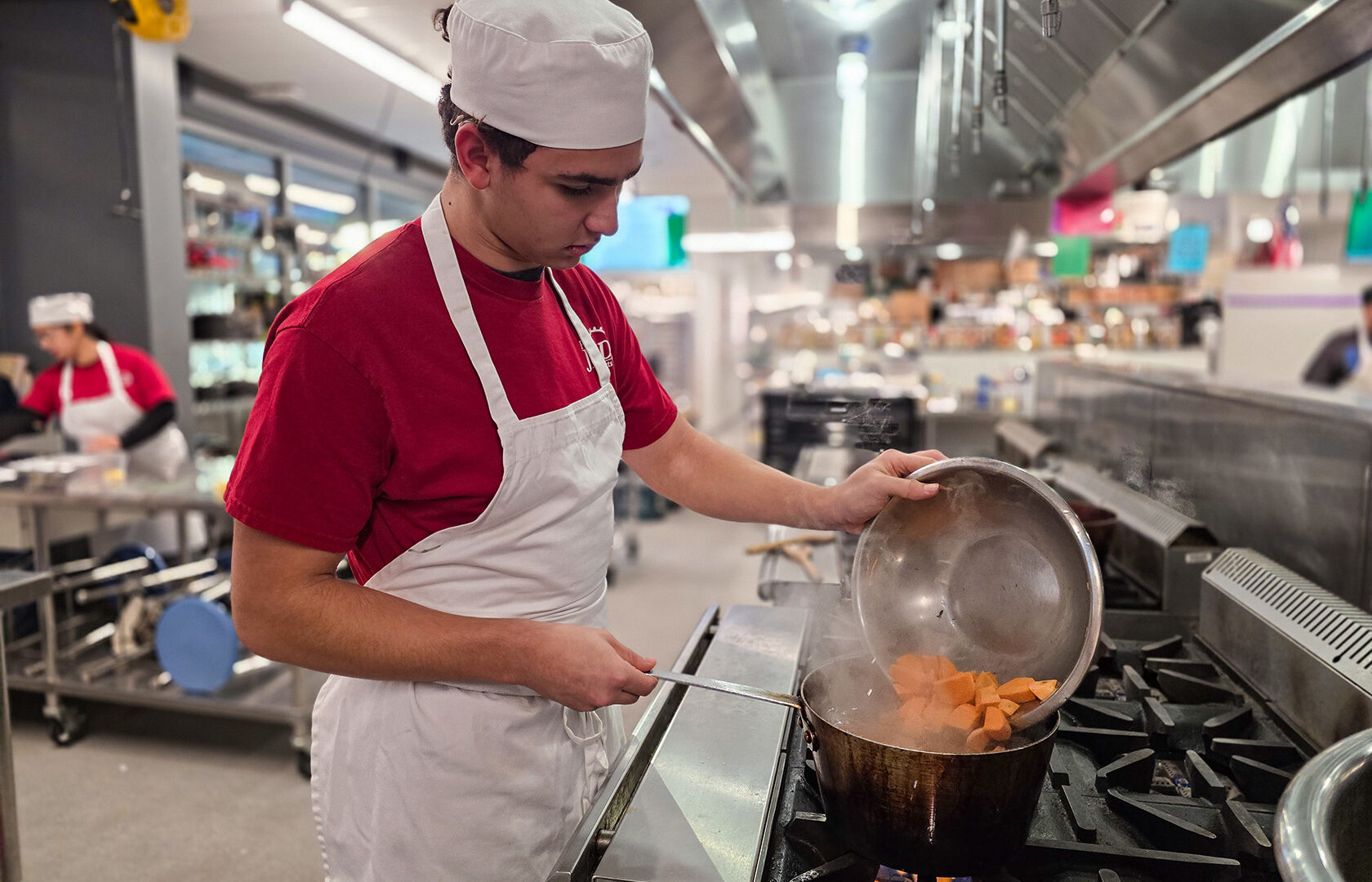 Student dumping food into boiling pot