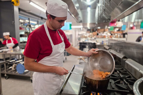 Student dumping food into boiling pot