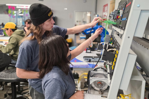 Two students placing wires on circuit