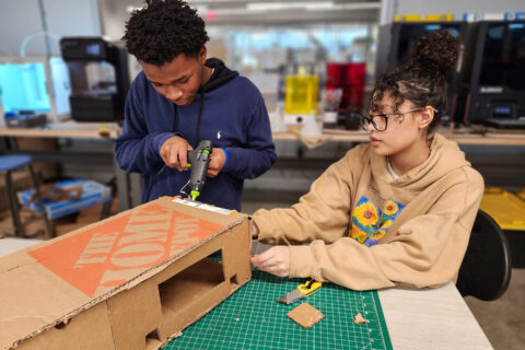 Students building cardboard bridge