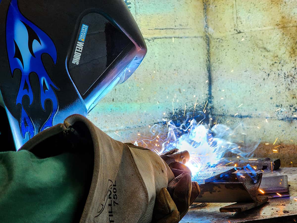 Student welding with blue flames and sparks