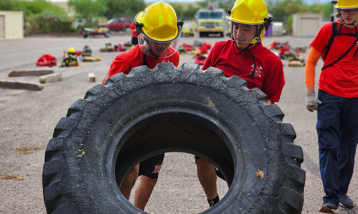 Two students flipping large tire