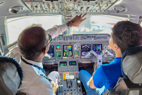 Commercial Pilot showing student some of plane controls in cockpit.