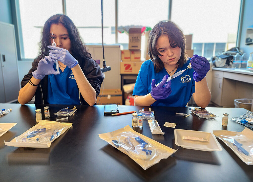 Students drawing compound into syringe