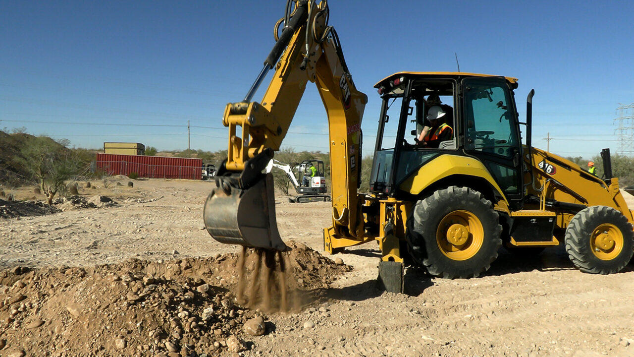 Student dumping dirt from backhoe