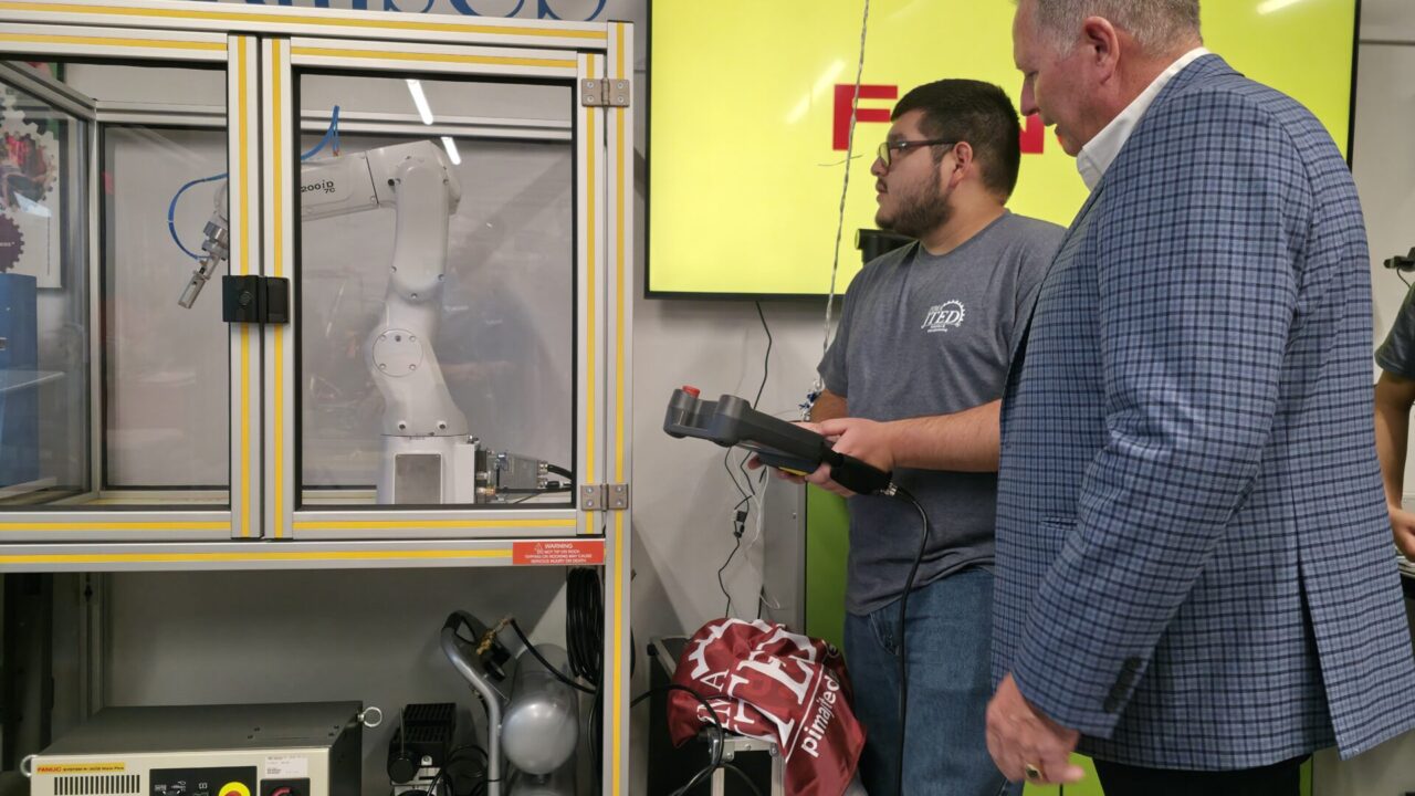 FANUC Rep showing student how to use robotic arm