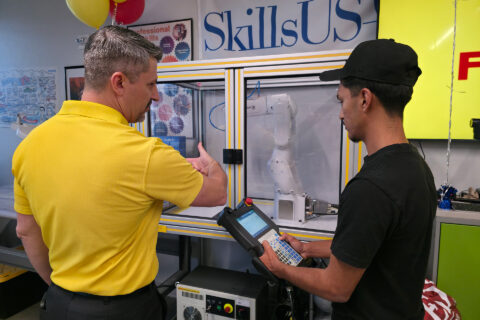 FANUC rep showing student how to use robotic arm