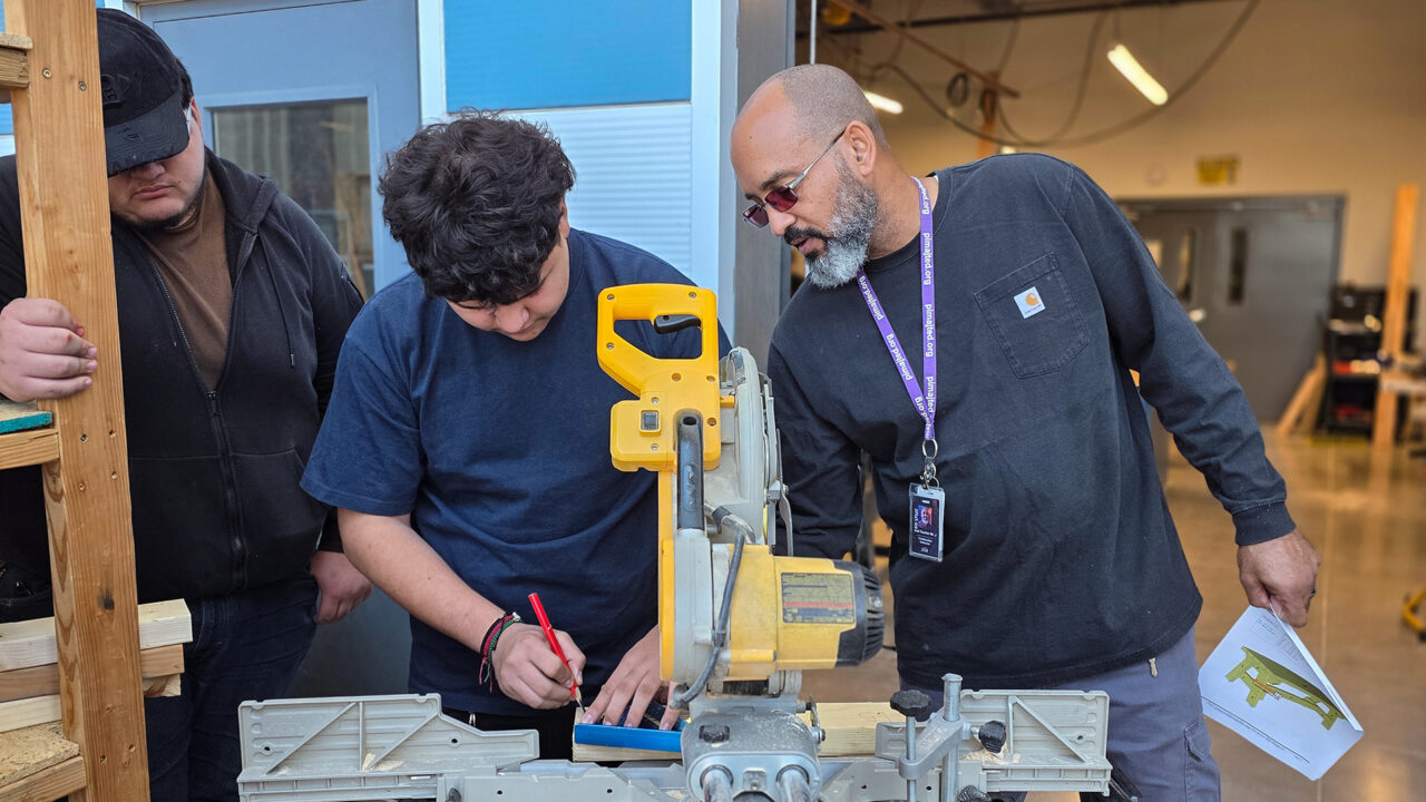 Teacher helping student with saw
