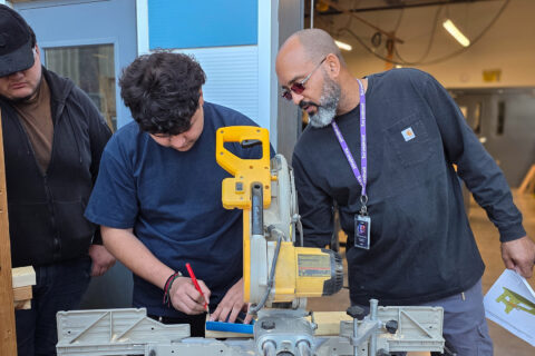 Teacher helping student with saw