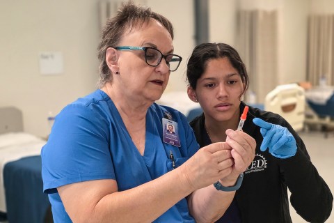 Student and instructor checking level of medication in syringe