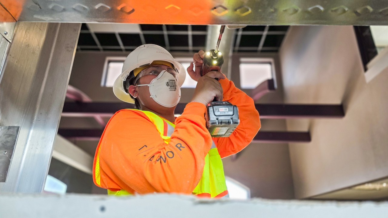 Construction intern using drill to drive screw